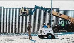  ?? ARIANA DREHSLER/GETTY-AFP ?? A Border Patrol officer stands guard Friday as work crews reinforce the border fence in San Diego. U.S. military troops are barred from conducting law enforcemen­t duties.