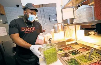  ?? JOHN MCCALL/SOUTH FLORIDA SUN SENTINEL ?? Prep cook Andrew Walker restocks cilantro at Bodega Taqueria y Tequila in Fort Lauderdale. A new employee at the restaurant, Walker received a $400 cash signing bonus as an incentive to take the job.