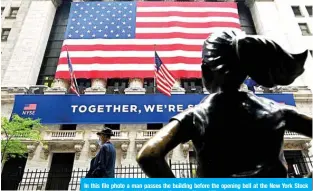  ??  ?? In this file photo a man passes the building before the opening bell at the New York Stock Exchange (NYSE) on Wall Street in New York City. – AFP