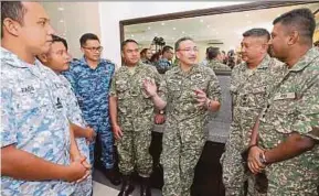  ?? PIC BY KHAIRULL AZRY BIDIN ?? Defence Minister Datuk Seri Hishammudd­in Hussein (centre) speaking with members of the armed forces at the Lok Kawi Army Camp in Putatan yesterday.