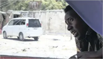  ?? SAID YUSUF WARSAME EPA-EFE ?? A SOMALI security officer takes cover with a civilian at the scene of a gun fight as others battle al-shabaab fighters who stormed a government building after exploding a car bomb in Mogadishu, Somalia, yeterday. |