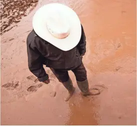  ?? MICHAEL CHOW/THE REPUBLIC ?? Left: Felix Corona walks through muddy waters at his ranch in Laveen on Feb. 19.