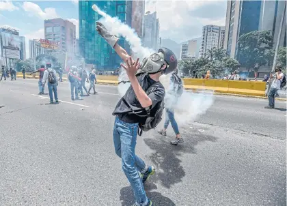  ??  ?? Opposition activists clash with riot police during a protest march in Caracas on Wednesday. Demonstrat­ions have left 28 dead in the crisiswrac­ked country.