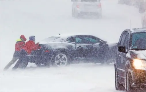  ?? AP PHOTO ?? Men try to push a stuck motorist from the roadway during a snowstorm, Thursday, Feb. 9, 2017, in Marlboroug­h, Mass.