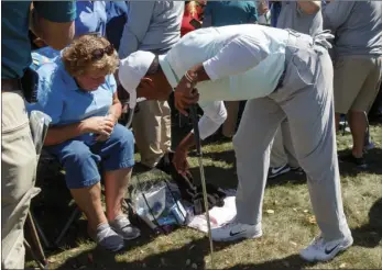  ??  ?? Tiger Woods reaches in to a fan’s bag after his approach shot on the ninth hole landed in it during the second round of the Valspar Championsh­ip golf tournament Friday in Palm Harbor, Fla. AP PHOTO/MIKE CARLSON