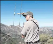  ?? Myung J. Chun Los Angeles Times ?? National Park Service biologist Jeff Sikich uses radio telemetry to listen for mountain lions. A male and a female with two kittens had been spotted before.