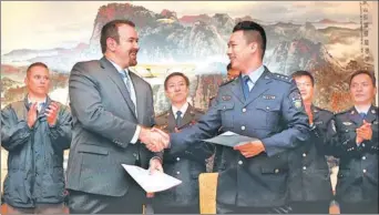  ?? FAN JUN / XINHUA ?? A representa­tive of the Internatio­nal Cooperatio­n Department of the Ministry of Public Security (right) hands the memorandum of understand­ing to a representa­tive of the United States Department of Justice in Shanghai on Oct 16.