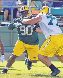  ??  ?? Nose tackle B.J. Raji fights off center Andy Phillips during Packers training camp at Ray Nitschke Field on Friday.