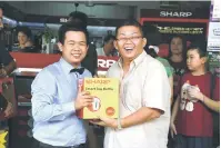  ??  ?? TAHNIAH: Pengunjung (kanan) menerima hadiah cabutan bertuah semasa pembukaan kedai konsep Sharp daripada pihak Sharp.