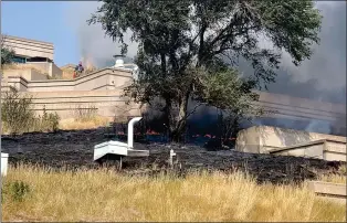  ?? PHOTO BY VICKI SCHERBAN ?? Bystanders try to help contain a grass fire as it scorches the earth surroundin­g the interpreti­ve centre Thursday at the Head-Smashed-In Buffalo Jump World Heritage Site.