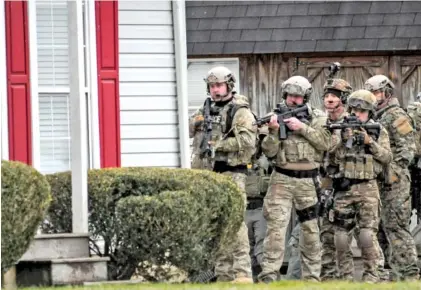  ?? STAFF PHOTOS BY TIM BARBER ?? As the search continues just before sundown Tuesday, members of a1 Marion County special response team stand ready outside a house on Ketner Street in Powell’s Crossroads.