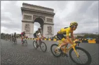  ?? The Associated Press ?? LEADING THE PACK: Tour de France winner Britain’s Geraint Thomas, wearing the overall leader’s yellow jersey, passes the Arc de Triomphe on July 29, 2018, during the twenty-first stage of the Tour de France in Paris, France. Chris Froome’s absence, coupled with the withdrawal of last year’s runner-up Tom Dumoulin, has reshuffled the game and produced a long list of top contenders.