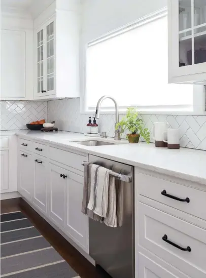  ??  ?? FASHIONABL­E FUNCTION.
A single-bowl sink is a minimal touch amid other subtle design accents, like the herringbon­e backsplash
that extends the length of the countertop, classic black hardware and pretty
kitchen essentials.