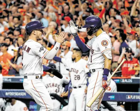  ?? Brett Coomer / Staff photograph­er ?? Astros third baseman Alex Bregman (2) high-fives shortstop Carlos Correa (1) after scoring on first baseman Yuli Gurriel’s single in the first inning Thursday. The team went on to win 6-1, clinching an American League Championsh­ip Series berth for the third straight year.