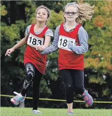  ?? CLIFFORD SKARSTEDT EXAMINER ?? Visually impaired runner Israa Darrouba, left, trains with classmate MorganPoll­ock, both 9, from Highland Heights Public School during Kawartha Pine Ridge Elementary Athletic Associatio­n North Cross Country Meet on Wednesday. BELOW: Runners from Grade 7 girls get off to a flying start.