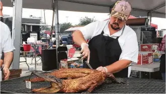  ?? Jody Schmal / Houston Chronicle ?? Grant Pinkerton served smoked alligator at the Houston Barbecue Festival.