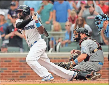  ?? John Bazemore / The Associated Press ?? Atlanta’s Brandon Phillips drives in the game-winning run with a base hit as Miami Marlins catcher A.J. Ellis watches.
