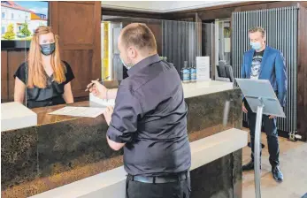  ?? FOTO: AH ?? Das Rezeptions­personal und der Hoteldirek­tor des Bodensee-Hotels Sonnenhof in Kressbronn-Rettersche­n, Thomas Riethmülle­r (rechts), testen die Abläufe beim Betreten und Einchecken des Hauses.