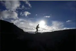  ?? GREGORY BULL — THE ASSOCIATED PRESS ?? Allen Mozo, of Haleiwa, Hawaii, carries an offering to an alter below the Mauna Loa volcano near Hilo, Hawaii, on Thursday.