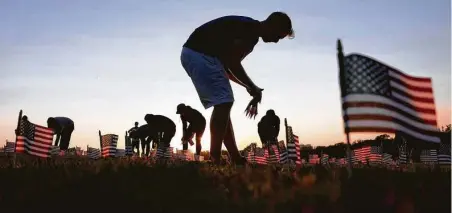  ?? Win McNamee / Getty Images ?? Volunteers with the COVID Memorial Project install 20,000 American flags on the National Mall to mark the lives lost to the virus.