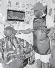  ?? PHOTO BY CHRISTOPHE­R THOMAS ?? George Miller, a barber based in Albert Town, Trelawny, shaves a customer in a display of his barbering skill despite having lost one hand in an accident in 1995.