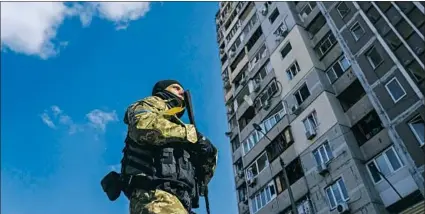  ?? Marcus Yam Los Angeles Times ?? A SOLDIER in Ukraine’s army guards a war-damaged apartment building in the Pozniaky neighborho­od of Kyiv.