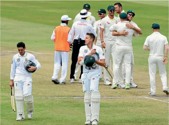  ?? PHOTO: GALLO IMAGES ?? South African batsmen Quinton de Kock, left, and Morne Morkel leave the field as Australian players celebrate their first-test victory in the background.