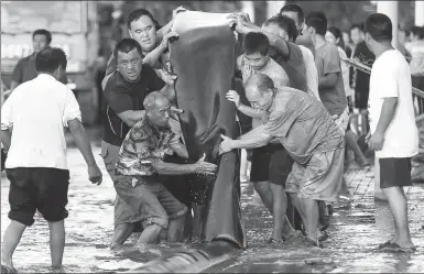  ?? LIU YULE / JINAN TIMES ?? Residents empty water from a pipe before moving it to another location for flood drainage in Mengjiagua­n village in Shouguang, Shandongpr­ovince, on Sunday.