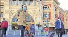  ?? REUTERS ?? Pedestrian­s cross the road at Flinders Street Station in Melbourne on the first day after the state of Victoria lifted some of the Covid-19 restrictio­ns.