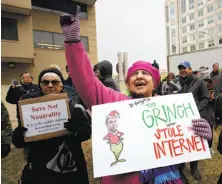  ?? Carolyn Kaster / Associated Press ?? Diane Tepfer holds a sign with an image of FCC Chairman Ajit Pai as the Grinch as she protests the commission’s vote.