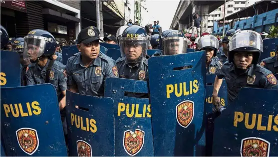  ??  ?? On duty: Manila policemen standing by as activists march to the Malacanang palace during an anti-Duterte protest on Nov 30, 2017. — AFP