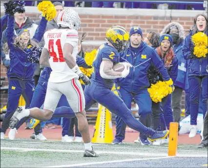  ?? Carlos Osorio
The Associated Press ?? Michigan running back Blake Corum outruns Ohio State safety Josh Proctor and stretches for one of his two touchdowns Saturday in the No. 3 Wolverines’ 30-24 victory in Ann Arbor, Mich.