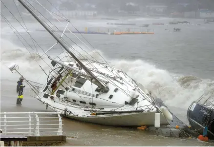  ?? Yonhap ?? Strong winds and waves from Typhoon Tapah drive two boats ashore in the southern city of Ulsan, Sunday. The typhoon, this year’s 17th, caused 390 flights to be canceled at Jeju Internatio­nal Airport, while all ferries to and from Incheon, Busan and Jeju Island were halted.