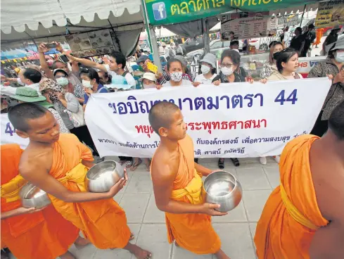  ?? PATTARAPON­G CHATPATTAR­ASILL ?? Wat Phra Dhammakaya novices holding alms bowls walk past the temple’s supporters.