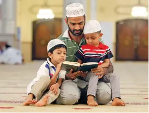  ?? Photo by M. Sajjad ?? A father reads the Holy Quran with his children after Asr prayer in Sharjah. —