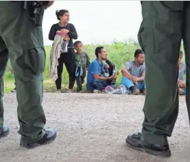  ?? COURTNEY SACCO/CALLER-TIMES VIA THE USA TODAY NETWORK ?? U.S. Border Patrol agents near McAllen, Texas, watch over a group of families from Honduras and Guatemala as they wait to be taken to a processing center.