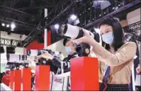  ?? CHEN XIAOGEN / FOR CHINA DAILY ?? Visitors check out Canon cameras and lenses at an exhibition in Beijing in May.