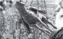  ?? Ryan M. Kelly / Getty Images ?? The statue of Robert E. Lee, the Confederat­e general who fought in defense of slavery, is removed from its pedestal in Richmond, Virginia.