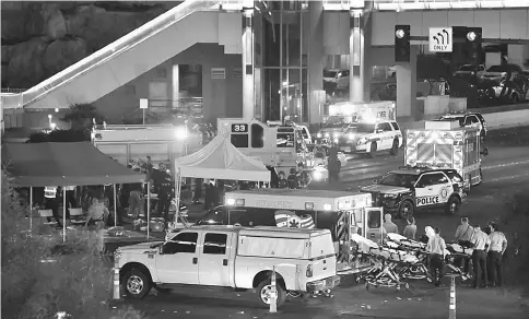  ?? — AFP photo ?? Police and rescue personnel gather at the intersecti­on of Las Vegas Boulevard and Tropicana Ave after the mass shooting.