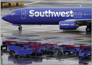  ?? (AP) ?? A Southwest Airlines jet passes unused luggage carts as it arrives in December at Sky Harbor Internatio­nal Airport in Phoenix.