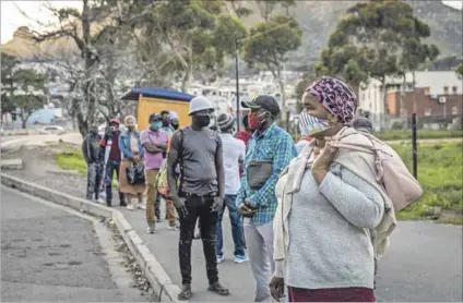  ?? Photo: Dwayne Senior/bloomberg/getty Images ?? A question of access: Being dependent on public transport, such as these people at a bus stop in Imizamo Yethu in Cape Town are, reduces one’s chances of getting vaccinated.