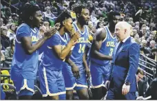  ?? AP PHOTO/ANDY NELSON ?? UCLA coach Mick Cronin (right) walks past as UCLA guard Will McClendon (left) guard Dylan Andrews (second from left) forward Kenneth Nwuba (14) and forward Adem Bona (3) cheer their teammates against Oregon during the second half of an NCAA college basketball game on Feb. 11 in Eugene, Ore.