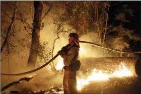  ?? MARCIO JOSE SANCHEZ — THE ASSOCIATED PRESS ?? A firefighte­r holds a water hose while fighting a wildfire Saturday in Santa Rosa