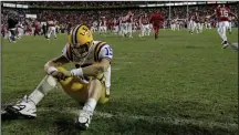  ?? (AP file photo) ?? LSU quarterbac­k Matt Flynn sits on the field as Arkansas players celebrate their victory over the top-ranked Tigers. Flynn was intercepte­d by Arkansas’ Matterral Richardson on a two-point conversion attempt in the third overtime to give the Razorbacks the victory.