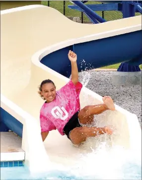  ?? File photo/Sierra Bush ?? A girl enjoys the water slide at the Siloam Springs Family Aquatic Center during the Siloam Springs Police Department’s National Night Out event in August 2019. The aquatic center is scheduled to reopen on June 18 at 50 percent capacity.