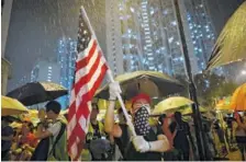  ?? AP PHOTO/VINCENT YU ?? A protester waves a U.S. flag as hundreds of protesters gather outside Kwai Chung police station in Hong Kong on Tuesday.