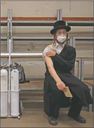  ?? (AP/Oded Balilty) ?? An ultra-Orthodox Jewish man rests after receiving his second dose of the Pfizer vaccine at a coronaviru­s vaccinatio­n center set up at a synagogue in Bnei Brak, Israel.