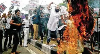 ??  ?? NEW DELHI: Indian traders shout slogans as they burn an effigy representi­ng a tax worker during a protest against the forthcomin­g Goods and Services Tax (GST) rates. — AFP