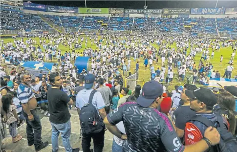  ?? ?? MATCH TRAGEDY: Fans take to the pitch at the stadium in Cuscatlan, El Salvador, following the fatal stampede.