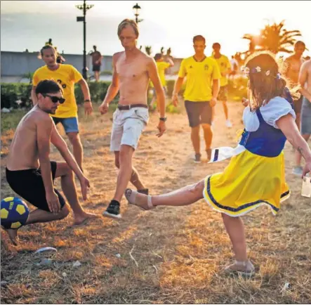  ??  ?? GOL CLÁSICO. Esta seguidora sueca, vestida con un típico traje del país, chuta un balón y parece que va a ser gol.